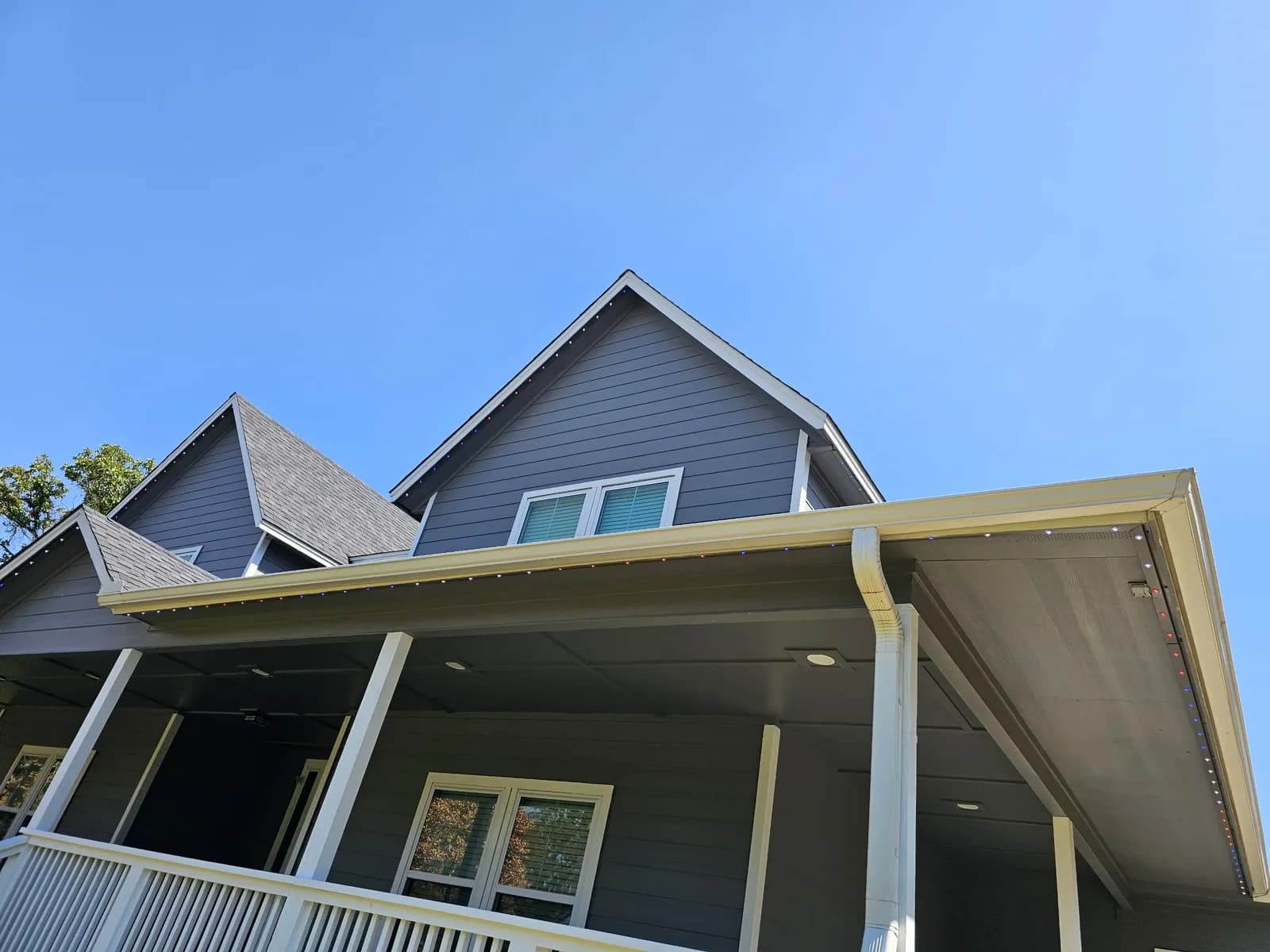 New seamless gutters on a gray two-story home with a wraparound porch