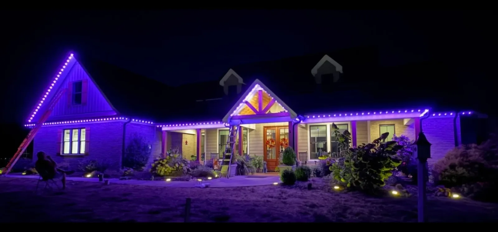 Wide panorama of a brick home lit in purple and white