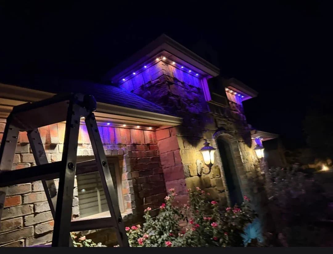 Stone home lit purple with the crew still on the ladder